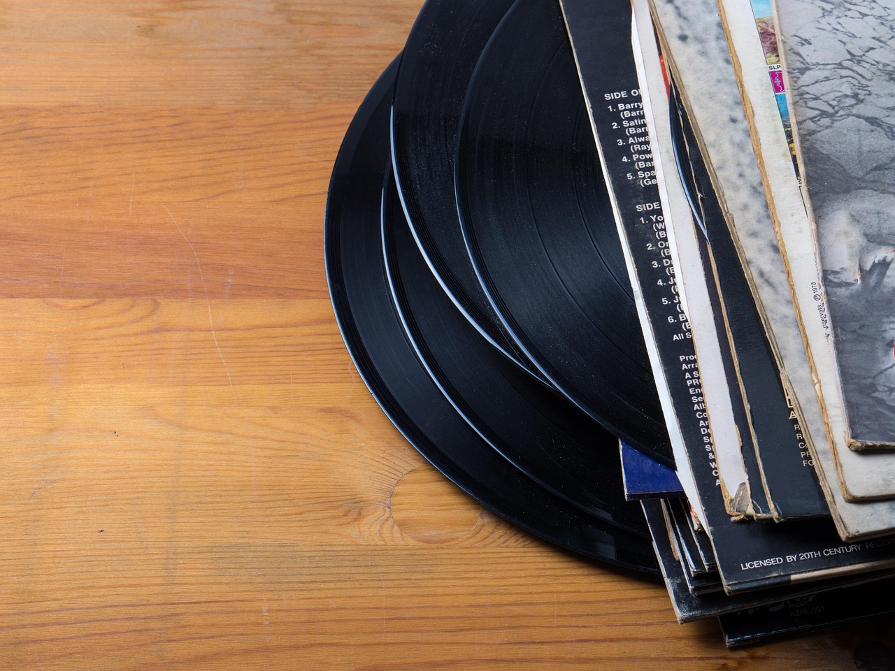 Vinili 45 giri vintage con stampe promozionali esposte su un tavolo di legno.