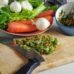 Due pentole con soffritto: una con burro, l'altra con olio d'oliva, su un piano di lavoro.