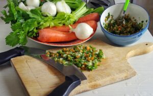 Due pentole con soffritto: una con burro, l'altra con olio d'oliva, su un piano di lavoro.