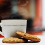 Biscotti per colazione su un tavolo, con tazza di caffè e frutta fresca accanto.