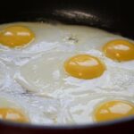 Uova in cottura in una pentola, con fumi e vapore che si alzano.