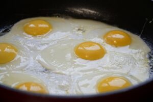 Uova in cottura in una pentola, con fumi e vapore che si alzano.